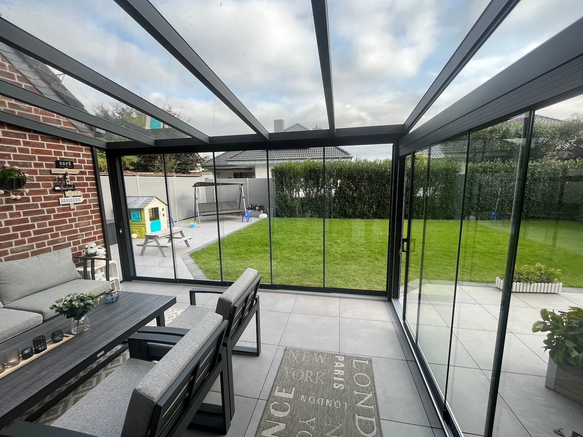 Wintergarten aus Aluminium mit Glasdach und Glasschiebewänden, Blick von innen in den Garten